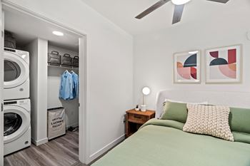 A bedroom with a bed and a washer and dryer and a closet
